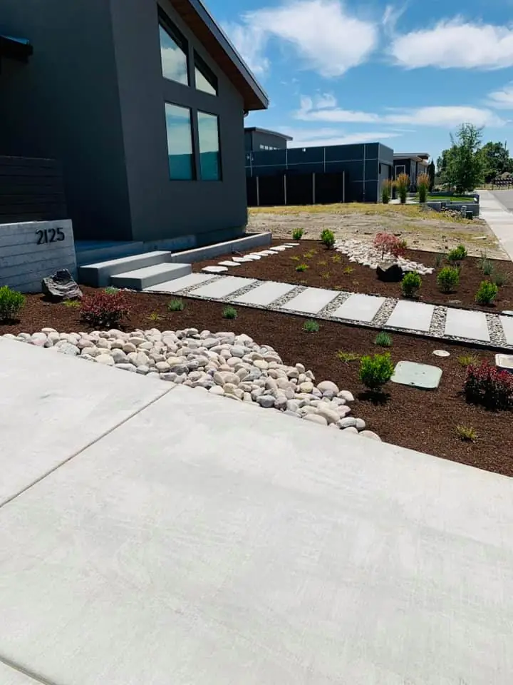 Modern home with new beds of river rock, bark and stepping pavers